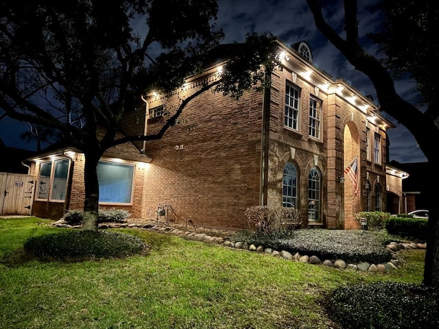 property exterior at night with a lawn