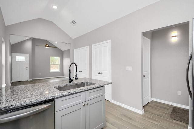 kitchen with lofted ceiling, sink, dishwasher, ceiling fan, and light stone countertops