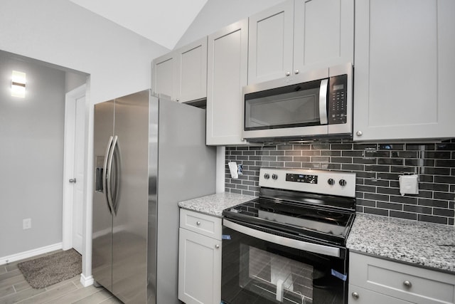 kitchen with tasteful backsplash, vaulted ceiling, appliances with stainless steel finishes, and white cabinets