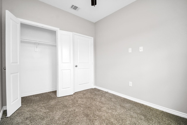 unfurnished bedroom with ceiling fan, dark carpet, and a closet