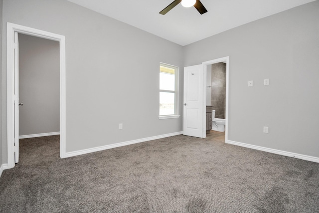 unfurnished bedroom featuring connected bathroom, dark carpet, ceiling fan, and a spacious closet