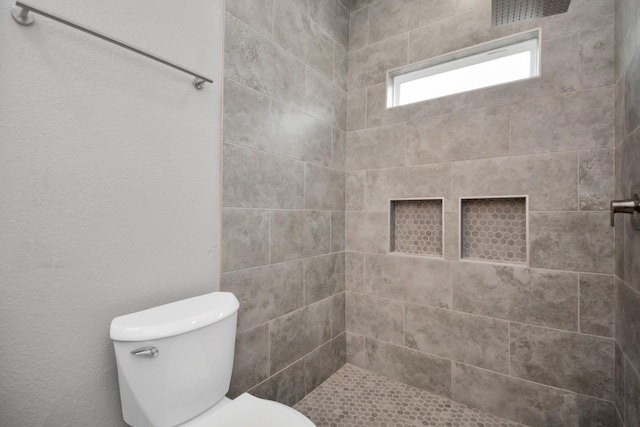 bathroom featuring toilet and tiled shower