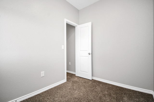 unfurnished room featuring dark colored carpet