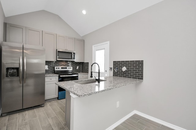 kitchen featuring sink, stainless steel appliances, light stone counters, white cabinets, and kitchen peninsula