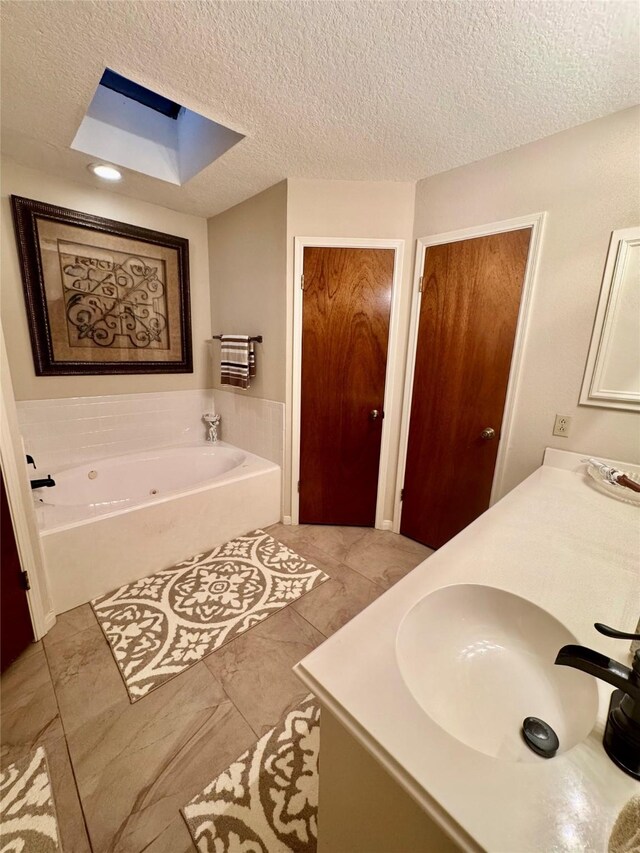125 Clear Spgs, Trinity, TX 75862 - bathroom featuring a skylight, a tub with jets, vanity, a textured ceiling, and recessed lighting