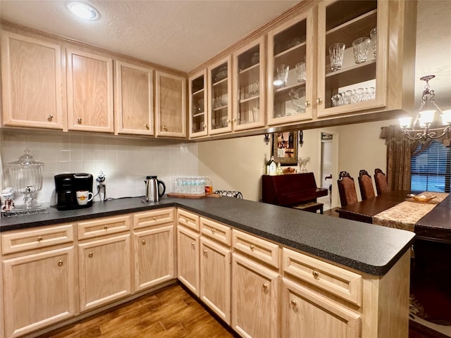 125 Clear Spgs, Trinity, TX 75862 - kitchen featuring light brown cabinets, a chandelier, a peninsula, dark wood-type flooring, and decorative backsplash