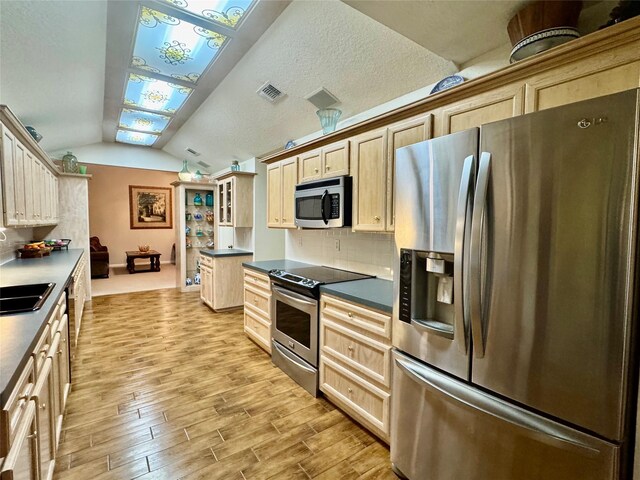 125 Clear Spgs, Trinity, TX 75862 - kitchen with stainless steel appliances, lofted ceiling, light wood-style floors, backsplash, and dark countertops
