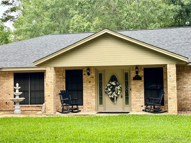 125 Clear Spgs, Trinity, TX 75862 - view of front of home featuring a shingled roof, brick siding, a front lawn, and covered porch