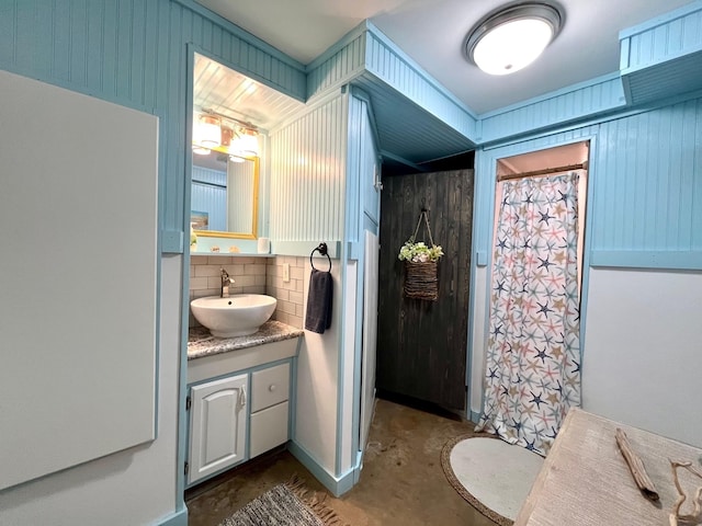 bathroom featuring concrete floors, vanity, wooden walls, curtained shower, and decorative backsplash