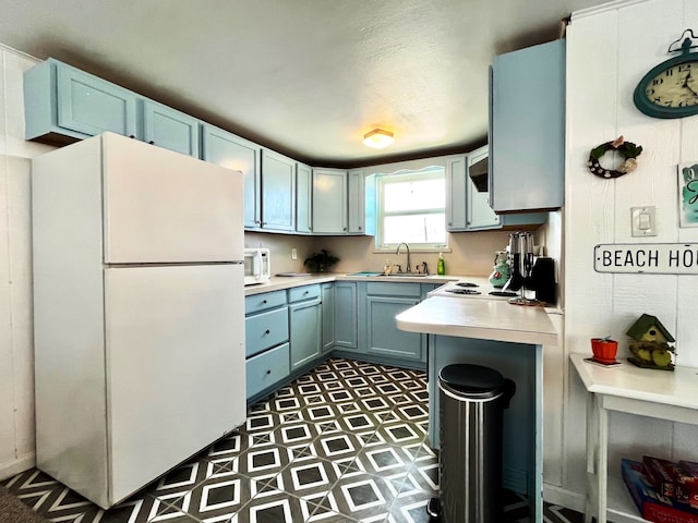 kitchen featuring blue cabinetry, white appliances, and sink