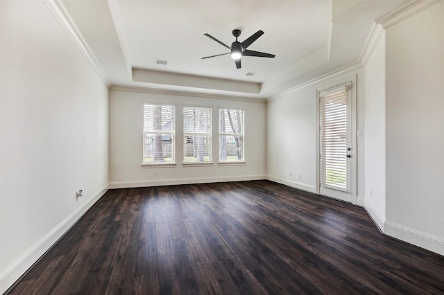 empty room featuring baseboards, a tray ceiling, dark wood finished floors, and a healthy amount of sunlight