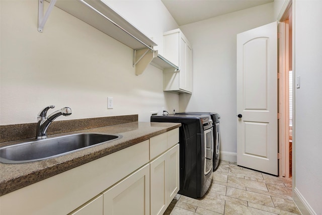 clothes washing area featuring cabinet space, baseboards, washer and dryer, and a sink