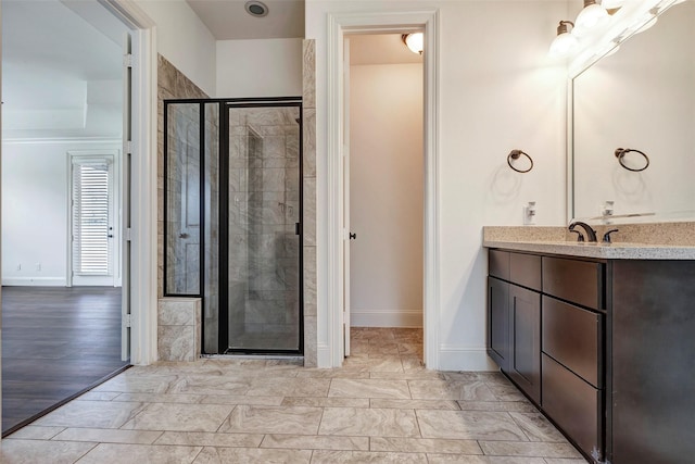 full bathroom featuring a stall shower, baseboards, and vanity