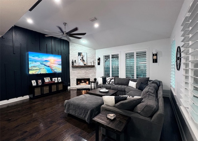 living area featuring a fireplace, visible vents, dark wood-type flooring, vaulted ceiling, and ceiling fan