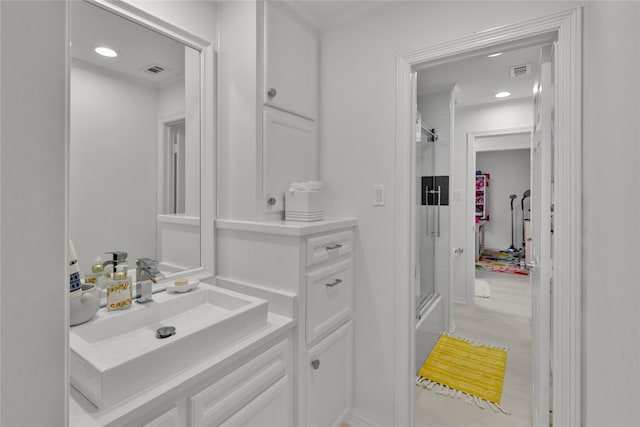 bathroom featuring a shower with door and vanity