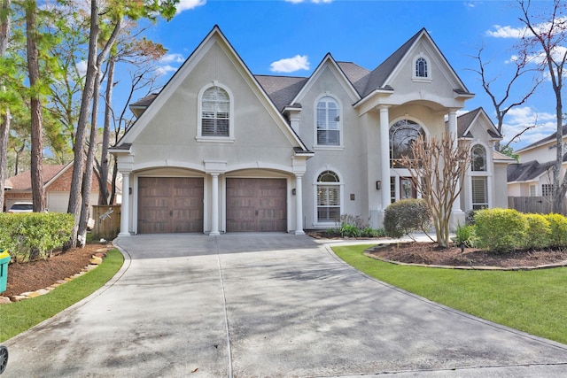 view of front of property with concrete driveway, a front yard, fence, and stucco siding