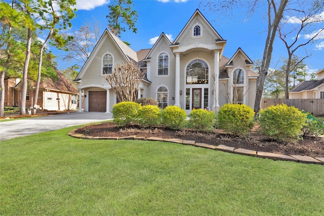 view of front of home with a garage, fence, driveway, stucco siding, and a front lawn