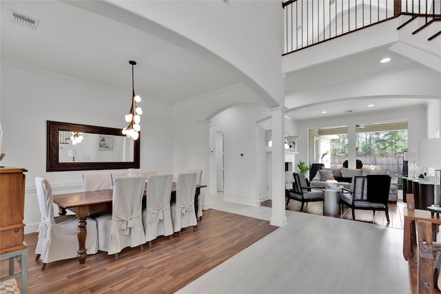 dining area with hardwood / wood-style flooring, ornamental molding, a high ceiling, and ornate columns