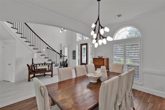 dining area with crown molding, wood-type flooring, and an inviting chandelier