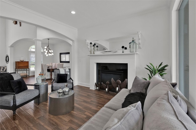 living room with decorative columns, crown molding, dark hardwood / wood-style floors, and an inviting chandelier