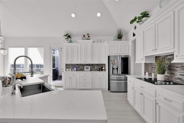 kitchen featuring sink, black electric stovetop, white cabinets, and stainless steel fridge with ice dispenser