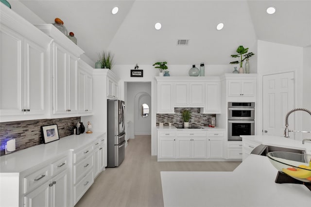 kitchen featuring lofted ceiling, stainless steel appliances, sink, and white cabinets