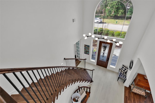 entrance foyer featuring a notable chandelier, a towering ceiling, and wood-type flooring