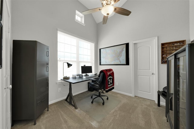 home office with baseboards, high vaulted ceiling, a ceiling fan, and light colored carpet