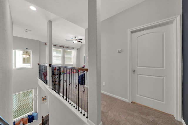 corridor with an upstairs landing, light colored carpet, visible vents, and baseboards