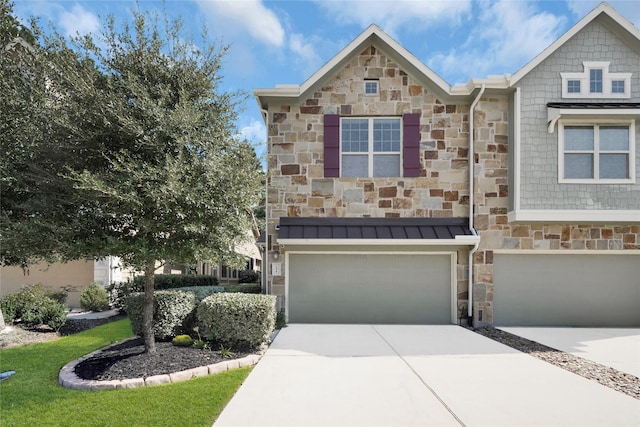 townhome / multi-family property featuring a garage, stone siding, concrete driveway, and a standing seam roof