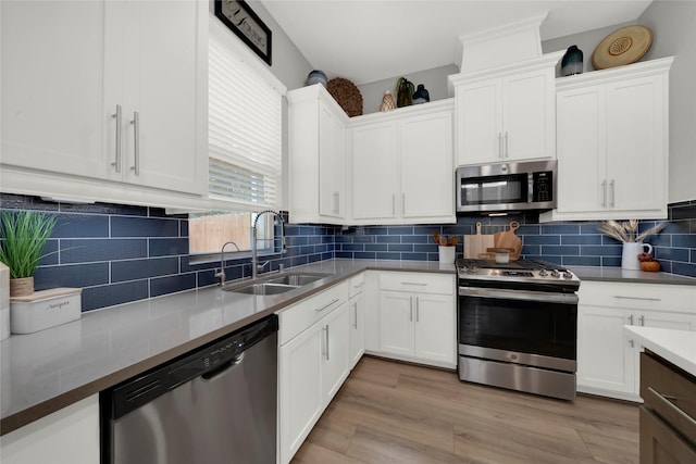 kitchen featuring appliances with stainless steel finishes, backsplash, a sink, and white cabinets