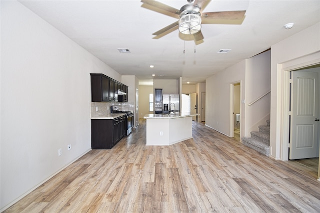 kitchen with a kitchen island with sink, decorative backsplash, stainless steel appliances, and light hardwood / wood-style floors