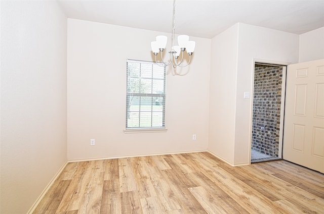 empty room with a chandelier and light hardwood / wood-style flooring