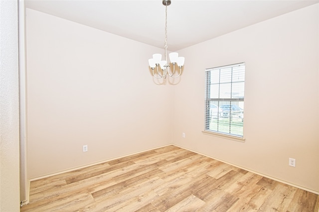 empty room featuring a chandelier and light hardwood / wood-style flooring