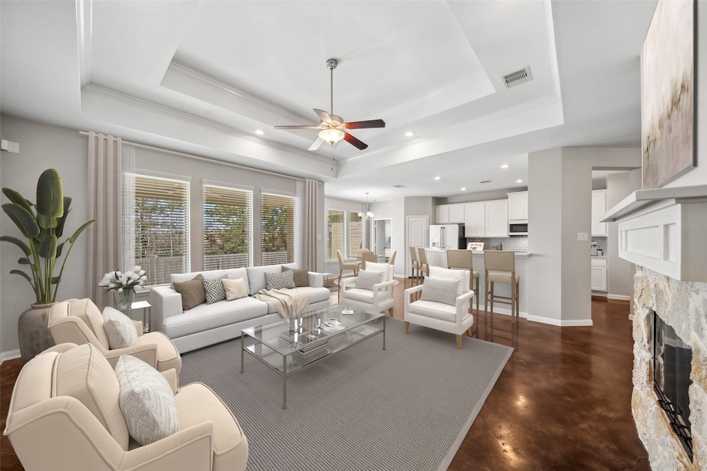 living room with ceiling fan, crown molding, a fireplace, and a tray ceiling