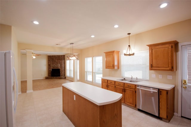 kitchen with sink, a kitchen island, a brick fireplace, stainless steel dishwasher, and white fridge