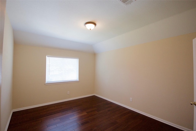 empty room with vaulted ceiling and dark hardwood / wood-style floors