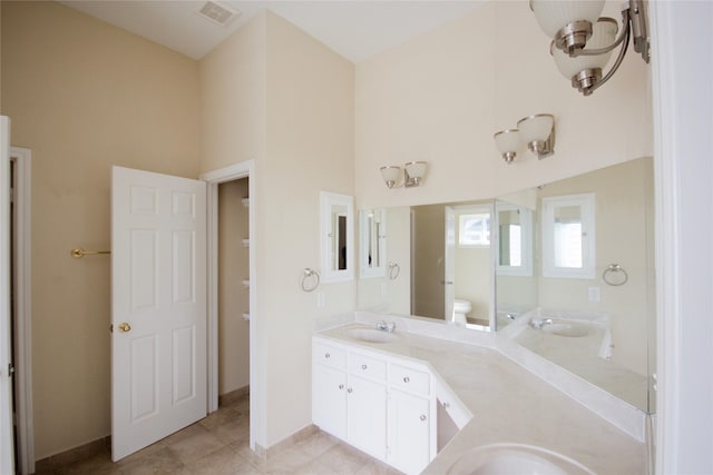 bathroom with vanity, toilet, tile patterned flooring, and a high ceiling