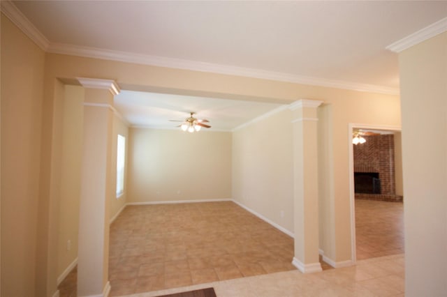 spare room featuring crown molding, a fireplace, decorative columns, and ceiling fan