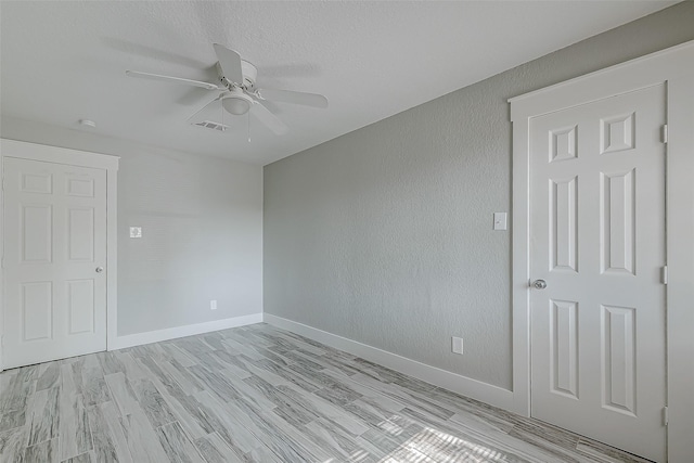 empty room featuring ceiling fan, a textured ceiling, and light hardwood / wood-style floors