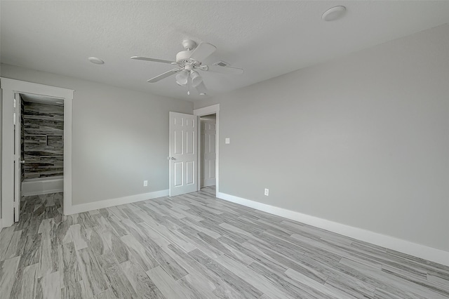 empty room with ceiling fan, light hardwood / wood-style floors, and a textured ceiling