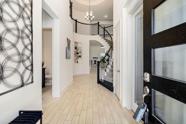 entryway featuring a high ceiling, a chandelier, and light wood-type flooring