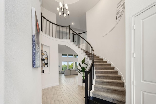 entrance foyer featuring a towering ceiling, a chandelier, and light hardwood / wood-style floors