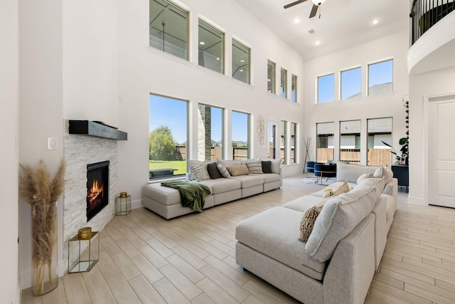 living room featuring ceiling fan, a fireplace, and light wood-type flooring