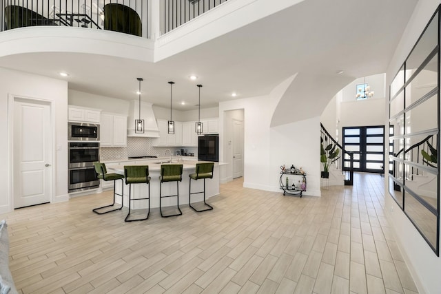 kitchen with white cabinetry, a kitchen island with sink, a kitchen breakfast bar, built in microwave, and decorative light fixtures