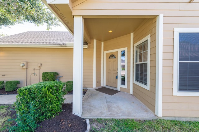 doorway to property featuring roof with shingles