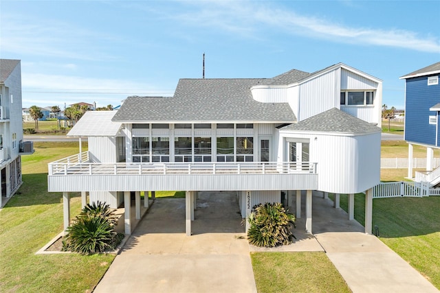 rear view of property with driveway, a shingled roof, a balcony, french doors, and a carport