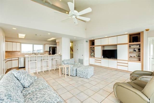 tiled living room featuring sink, a towering ceiling, and ceiling fan