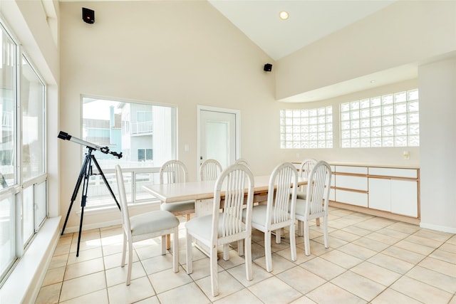 tiled dining room featuring high vaulted ceiling