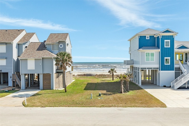 view of front of home featuring a front yard, a carport, a beach view, and a water view